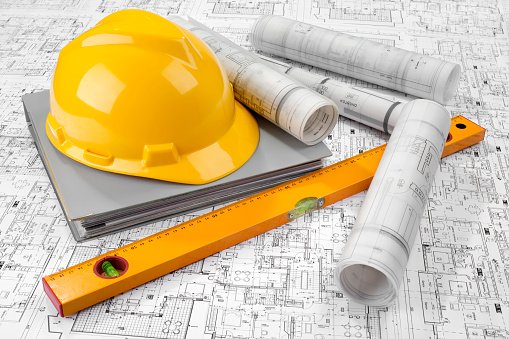 Yellow helmet, level, grey folder document and project drawings
